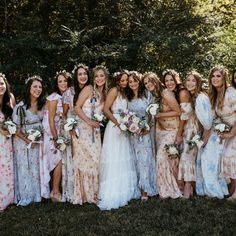 a group of women standing next to each other wearing dresses and holding bouquets in their hands