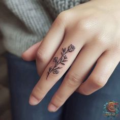 a woman's hand with a flower tattoo on her left thumb and the ring finger