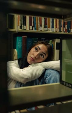 a woman sitting in front of a bookshelf with her arm wrapped around the neck