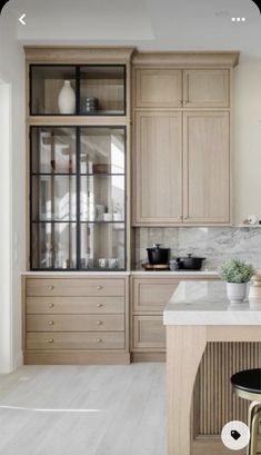 a kitchen with wooden cabinets and marble counter tops, along with two stools in front of the island