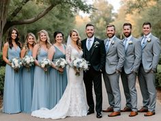 a group of people standing next to each other in front of trees and bushes with flowers