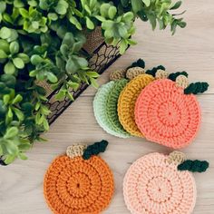 three crocheted pumpkins sitting on top of a table next to a potted plant