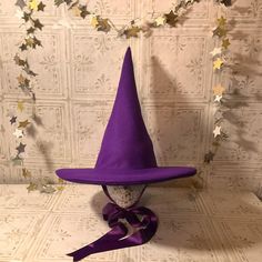 UPDATE: AUGUST 2023- These hats are now made with two layers of felt in the cone.  The double layer makes for a stronger hat which stands up on its own while still being light enough to be comfortable. Looking for a fun witch hat?  Who says that witches have to wear black?  Want to look like you stepped out of the pages of a fairy tale?  Searching for a unique hat for Halloween?  This is perfect for the practical witch who wants her hat to stay put while she soars through the night sky on her broomstick. These witch hats are made out of soft amethyst purple wool/rayon felt.  Satin ribbons tie under your chin.  Choose from a classic straight cone or a whimsical, crooked cone.   Wool Felt is a blend of 35% wool and 65% rayon.  It's a very soft, flexible fabric which makes a lightweight, comf Adjustable Flat Brim Costume Hat, Adjustable Brimmed Felt Costume Hat, Adjustable Brimmed Felt Hat For Costume, Adjustable Costume Bonnet, Adjustable Fedora Felt Hat For Halloween, Adjustable Brimmed Felt Hat For Costume Party, Curved Brim Costume Hat, Costume Hat With Curved Brim, Adjustable Costume Cap