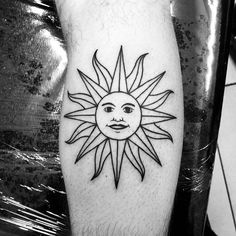 a black and white photo of a sun tattoo on the leg