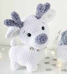 a crocheted white and gray stuffed animal next to a ball of string lights