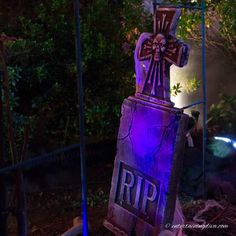 an old tombstone with a cross on it in the middle of a yard at night