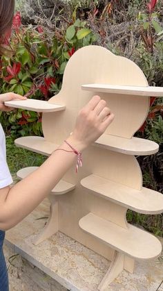 a woman is placing shelves on the back of a wooden chair with flowers in the background