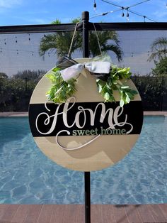 a sign that says home sweet home hanging from a pole next to a swimming pool