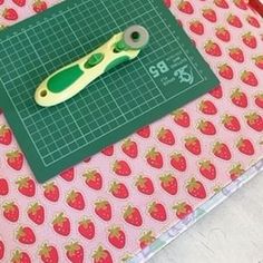 a pair of scissors sitting on top of a cutting board next to a green ruler