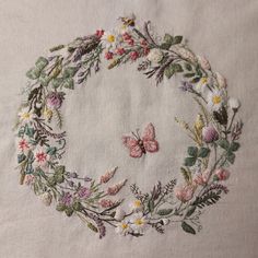 a white table cloth with embroidered flowers and butterflies on the edges, in a circle