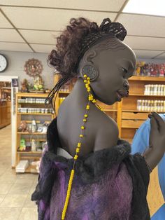 a mannequin wearing a purple and black dress with yellow beaded necklaces