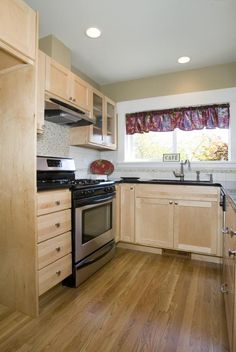 a kitchen with wood floors and cabinets in the corner, along with a stove top oven