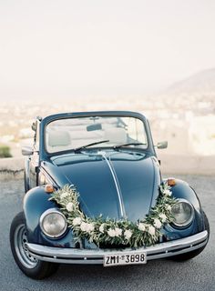 an old blue car decorated with flowers and greenery