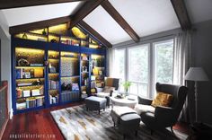 a living room filled with lots of furniture next to a large book shelf covered in books