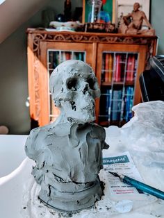 there is a statue made out of clay on the table next to a bookcase