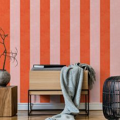 an orange and pink striped wallpaper is next to a wooden table with a plant on it