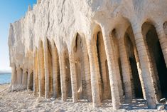 an old stone building with columns on the beach