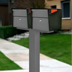 two mailboxes in front of a house on a street with grass and trees