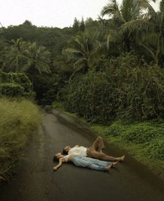 a person laying on the side of a road with palm trees in the back ground