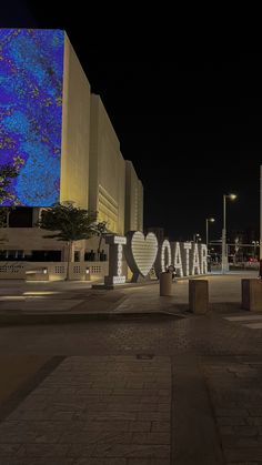 a large sign that says i love qatar in front of a building with lights on it