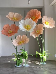 four vases with flowers in them sitting on the floor next to each other,