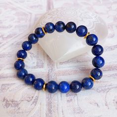 This handcrafted item is made from 8mm beads of Lapis Lazuli with gold coloured disc spacer beads. Sizes available 16cm. Alternative sizes are made on request, please contact me for details. It is elasticated so is easy to pull on & off. These beads are dyed to enhance the colour. This does not affect the healing properties of the stones. Take care when wearing with light coloured fabric as colour may transfer. Lapis Lazuli is a stone of communication, protection & knowledge. It helps to bring p Gold Lapis Lazuli Beaded Bracelets With Round Beads, Lapis Lazuli Beaded Bracelet Gift, Lapis Lazuli Gemstone Beaded Bracelet For Gifts, Lapis Lazuli Gemstone Beads Bracelet For Gift, Gift Rondelle Stretch Bracelet With Spacer Beads, Lapis Lazuli Gemstone Beaded Bracelets, Lapis Lazuli Beaded Bracelets With Gemstone, Lapis Lazuli Beaded Bracelets As Gift, Adjustable Lapis Lazuli Stretch Bracelet With Round Beads