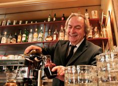 a man in a suit pours wine into glasses