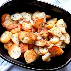 a black bowl filled with cooked potatoes on top of a blue and white table cloth