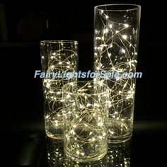 three glass vases with fairy lights on them