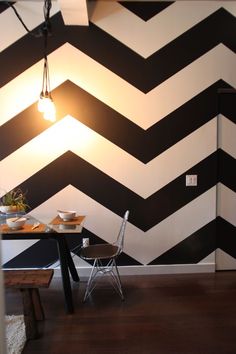 a dining room with black and white chevroned wallpaper, a chair and table