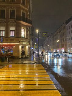 a wet city street at night with people walking on the sidewalk