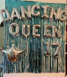 a sign that says dancing queen with balloons hanging from it's sides in front of a wall