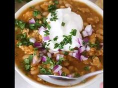 a white bowl filled with beans, onions and sour cream on top of a table