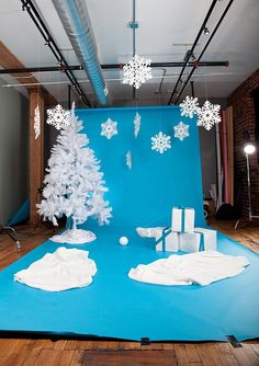 a blue backdrop with white snowflakes hanging from it's sides and trees in the middle