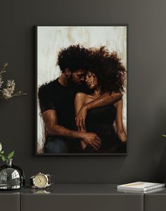 a painting of two people hugging each other on a wall next to a vase with flowers