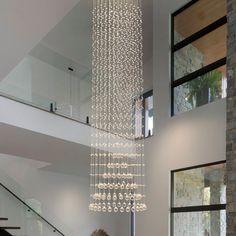 a chandelier hanging from the ceiling in a living room next to a staircase