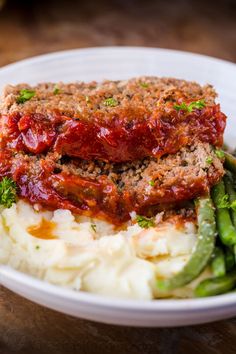 meatloaf, mashed potatoes and green beans in a white bowl on a wooden table