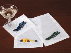 two napkins with cars on them and a wine glass sitting next to one another