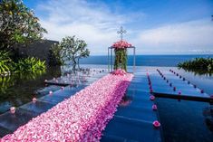 an outdoor wedding setup with pink flowers on the water