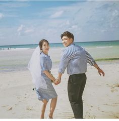 a man and woman holding hands on the beach