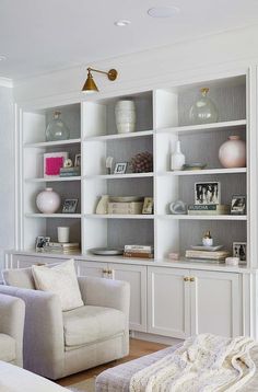 a living room filled with white furniture and lots of bookshelves on top of it