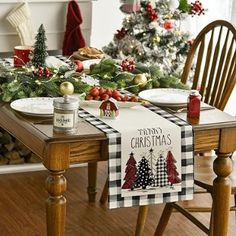 a dining room table decorated for christmas with holiday decorations on the table and trees in the background