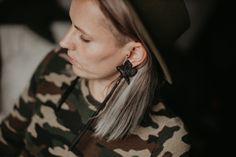 a woman with grey hair wearing a camo shirt and black hat