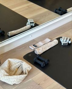 a yoga mat, towel and dumbbells sit on the floor in front of a mirror