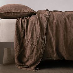 an unmade bed with brown linens and pillows