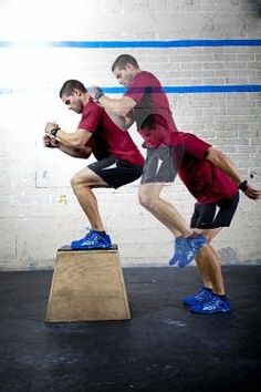 two men in red shirts and black shorts are doing squats on a wooden box