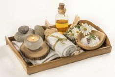 a wooden tray filled with towels, candles and other items on top of each other