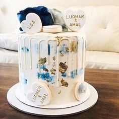 a white cake decorated with blue and gold icing sitting on top of a wooden table