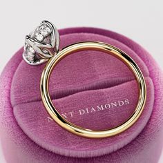 a diamond ring sitting on top of a pink velvet cushion with the words v t diamonds written below it