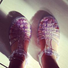 a person's feet wearing clear sandals with purple and white designs on them,